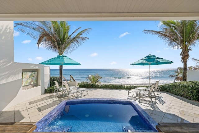 view of pool featuring a beach view, a water view, a pool, and a patio area