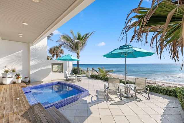 view of pool featuring a beach view, a patio area, and a water view