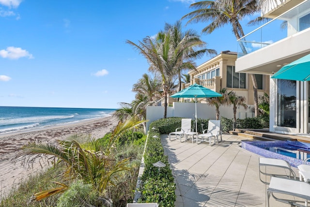 view of patio with fence, a view of the beach, and a water view