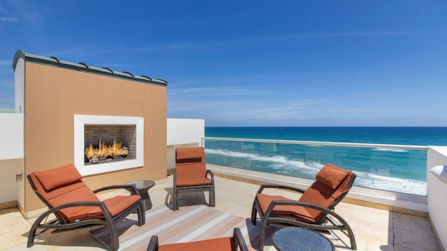 balcony with a water view and a lit fireplace