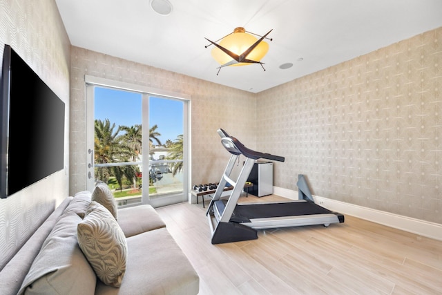 exercise area with baseboards, wood finished floors, and wallpapered walls