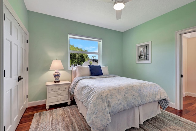 bedroom featuring a ceiling fan, a closet, baseboards, and dark wood-style flooring