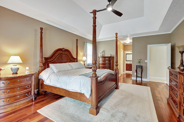 bedroom featuring a tray ceiling, ceiling fan, baseboards, and wood finished floors