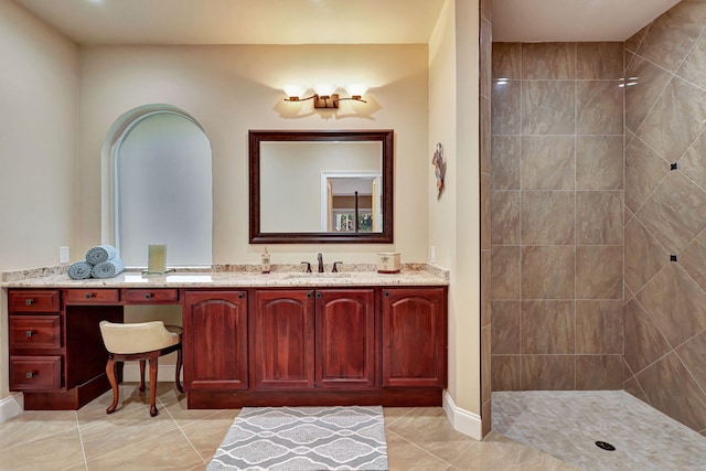 bathroom featuring tile patterned flooring, a tile shower, and vanity