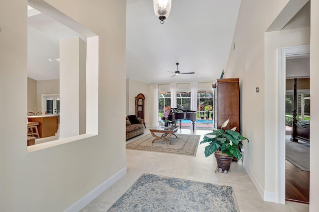 tiled entrance foyer with ceiling fan and baseboards