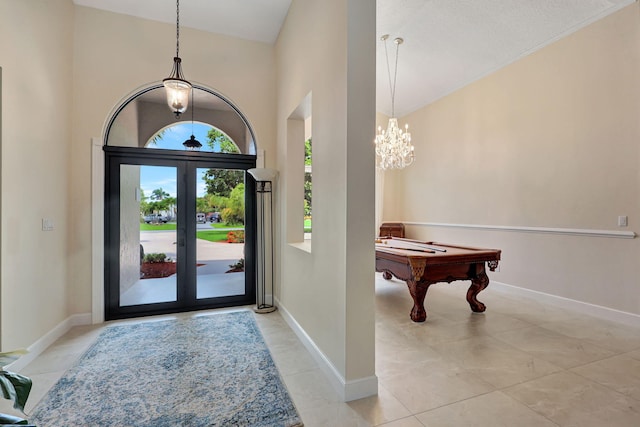 foyer featuring billiards, baseboards, a high ceiling, french doors, and a chandelier