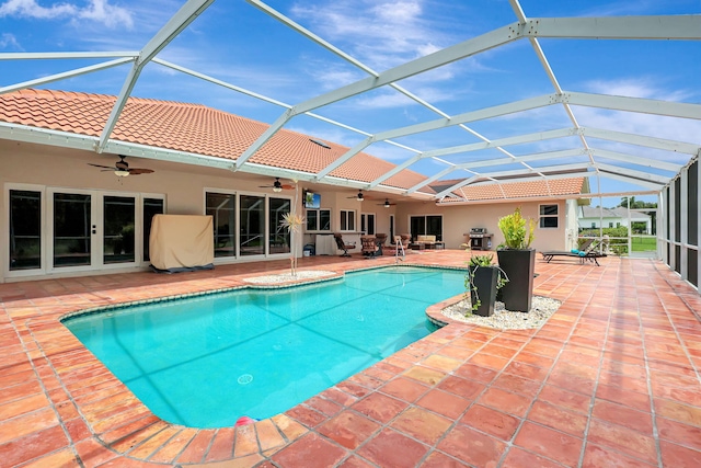 outdoor pool featuring a ceiling fan, glass enclosure, and a patio