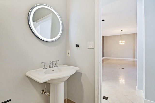 bathroom featuring an inviting chandelier, baseboards, and tile patterned floors