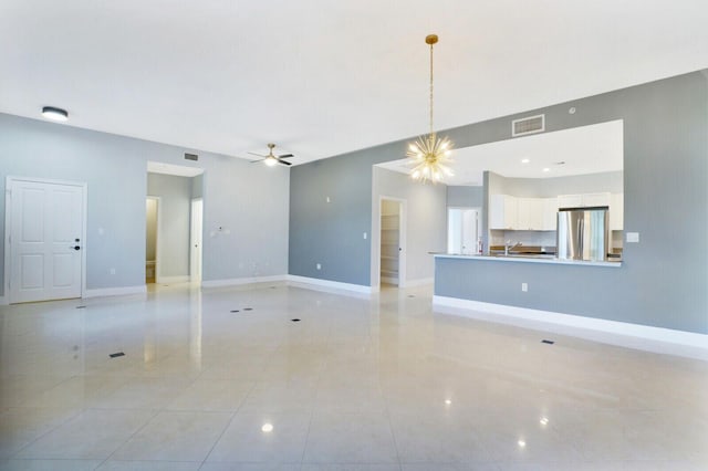 unfurnished living room with light tile patterned flooring, visible vents, baseboards, and ceiling fan with notable chandelier