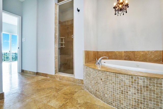 bathroom featuring an inviting chandelier, a shower stall, baseboards, and a bath