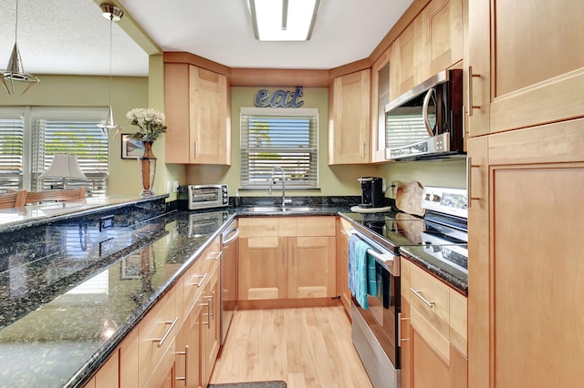 kitchen with light brown cabinets, stainless steel appliances, light wood-style floors, and a sink