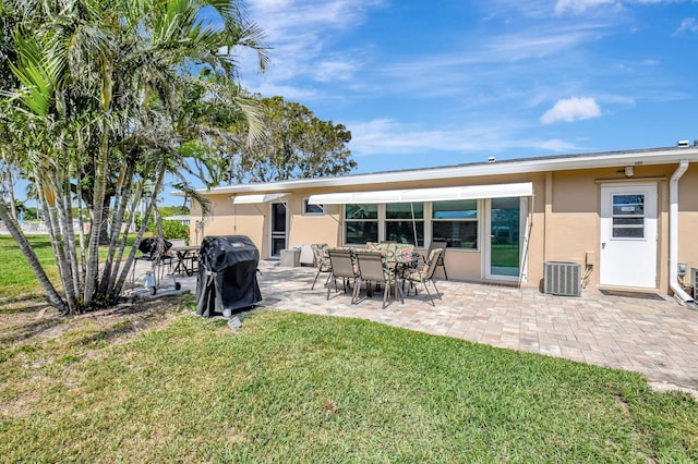 rear view of house featuring a yard, central AC unit, a patio area, and stucco siding