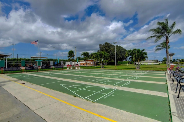 view of community with fence, shuffleboard, and a lawn