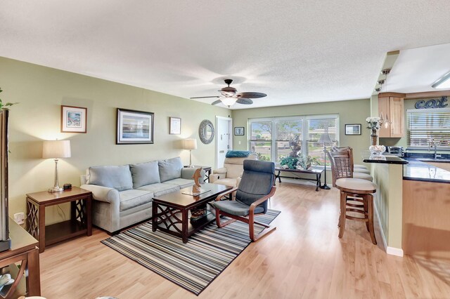 dining area with a textured ceiling, baseboards, and light wood-style floors