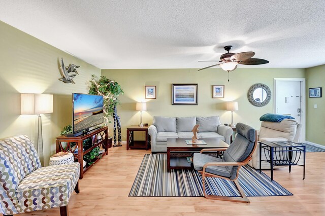 living area with light wood-type flooring, ceiling fan, and a textured ceiling