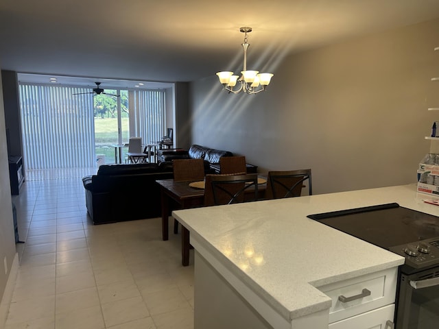 kitchen with light tile patterned floors, black / electric stove, ceiling fan with notable chandelier, white cabinetry, and pendant lighting