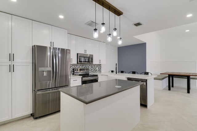 kitchen featuring tasteful backsplash, visible vents, a center island, appliances with stainless steel finishes, and a peninsula