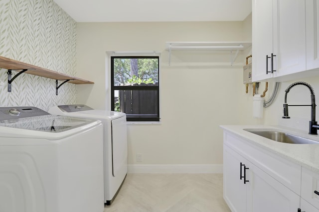 clothes washing area featuring wallpapered walls, baseboards, cabinet space, independent washer and dryer, and a sink