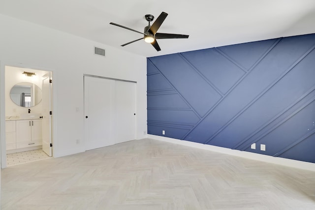 unfurnished bedroom with visible vents, a ceiling fan, ensuite bathroom, a sink, and a closet