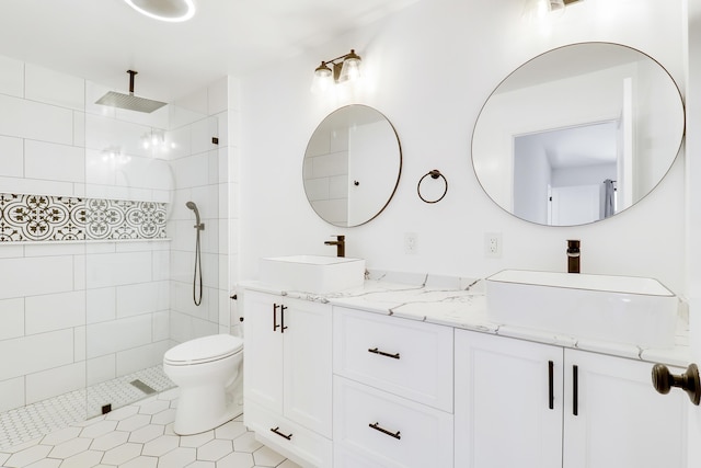 full bathroom with double vanity, toilet, a tile shower, and a sink