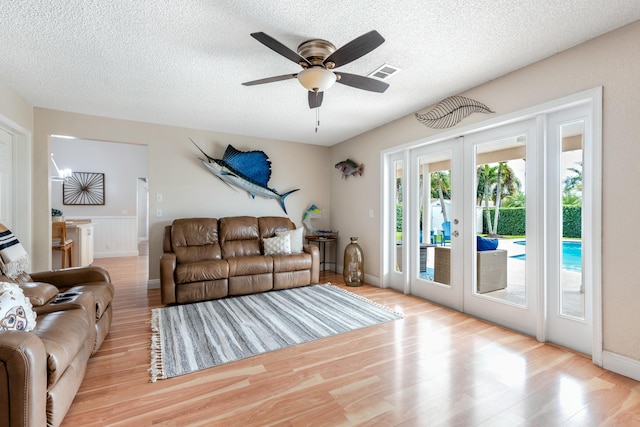 living area featuring french doors, visible vents, a textured ceiling, and wood finished floors