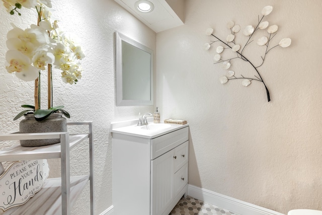 bathroom with a textured wall, baseboards, and vanity