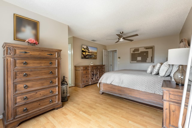 bedroom with a textured ceiling, light wood-style flooring, and a ceiling fan