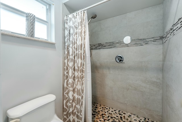 full bathroom with tiled shower and toilet