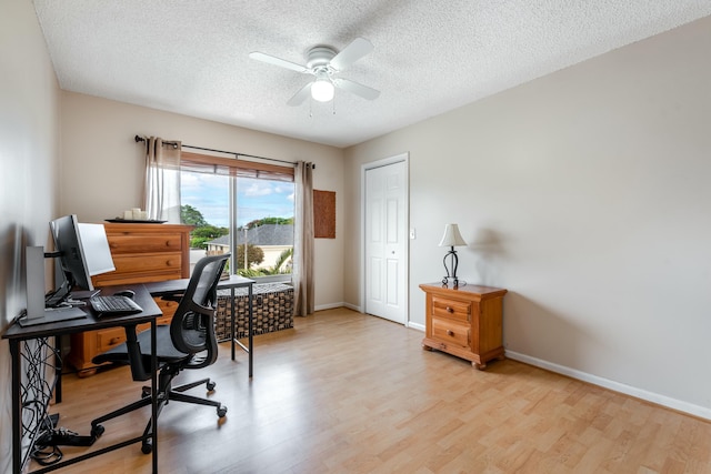 office area featuring ceiling fan, light wood-style flooring, baseboards, and a textured ceiling