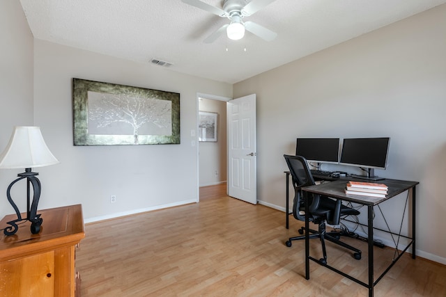 office featuring light wood finished floors, visible vents, baseboards, and a textured ceiling