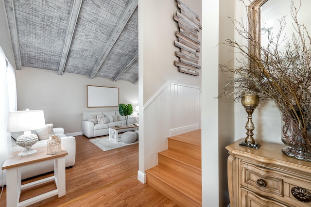 stairway featuring vaulted ceiling with beams, wood finished floors, and baseboards