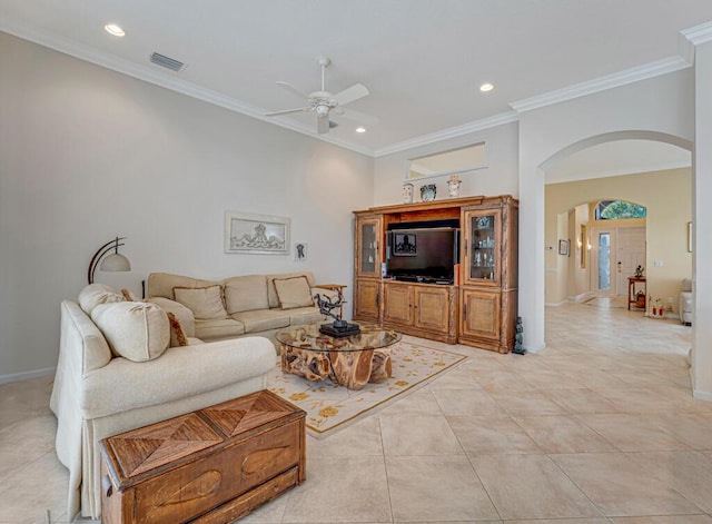 living room featuring arched walkways, visible vents, crown molding, and baseboards