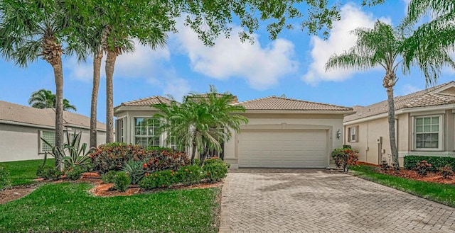 view of front of property with decorative driveway, a tile roof, an attached garage, and stucco siding