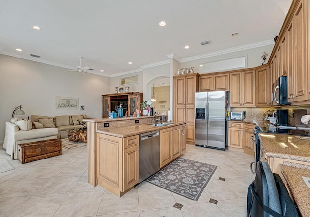 kitchen with light stone counters, arched walkways, appliances with stainless steel finishes, open floor plan, and a sink