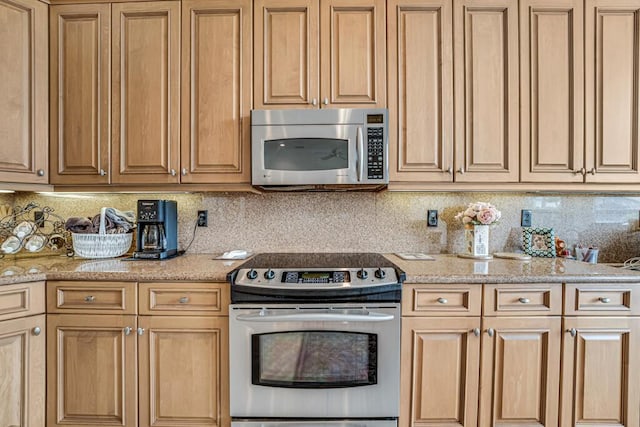 kitchen featuring stainless steel appliances, backsplash, and light stone countertops