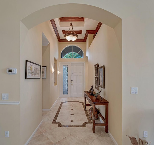 foyer entrance with a tray ceiling, arched walkways, crown molding, a towering ceiling, and baseboards