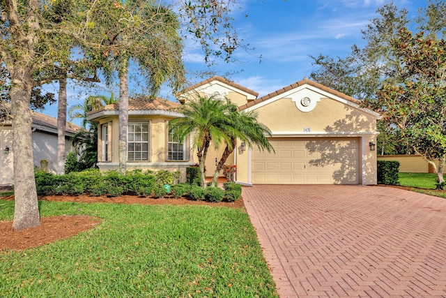 mediterranean / spanish-style home with a garage, a tile roof, decorative driveway, stucco siding, and a front yard