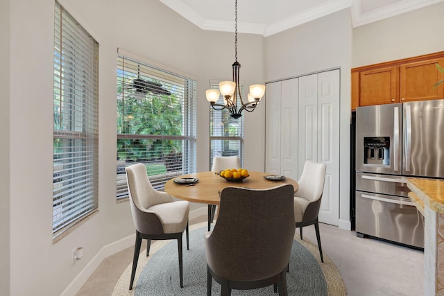 dining space featuring a chandelier, crown molding, a towering ceiling, and baseboards