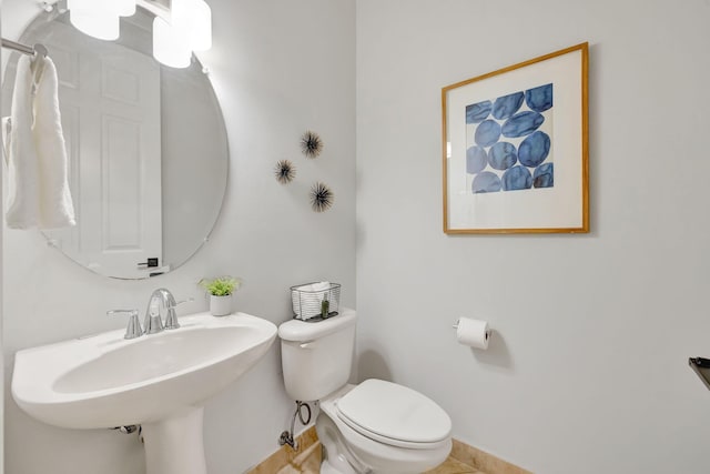 bathroom with toilet, baseboards, and a sink