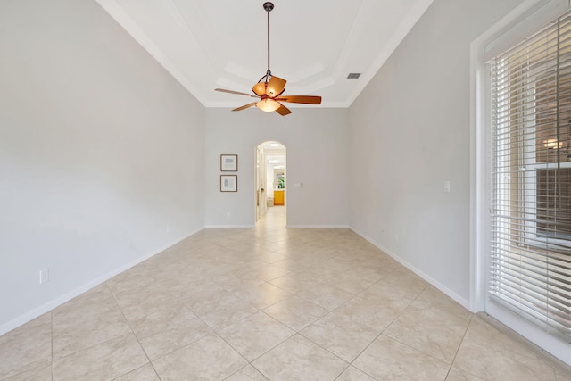 spare room with light tile patterned floors, baseboards, visible vents, arched walkways, and a ceiling fan