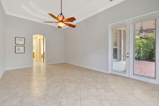 empty room featuring arched walkways, french doors, a ceiling fan, light tile patterned flooring, and baseboards