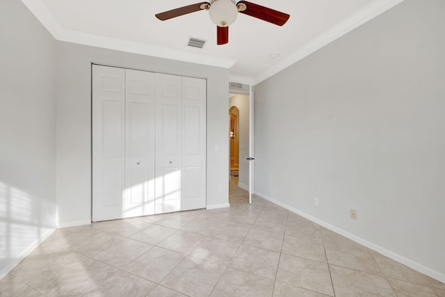 unfurnished bedroom featuring arched walkways, a closet, visible vents, ornamental molding, and baseboards