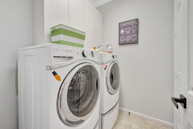 laundry room featuring washing machine and dryer, cabinet space, baseboards, and light tile patterned floors