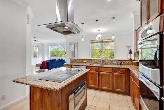 kitchen featuring brown cabinets, crown molding, a sink, island range hood, and a peninsula