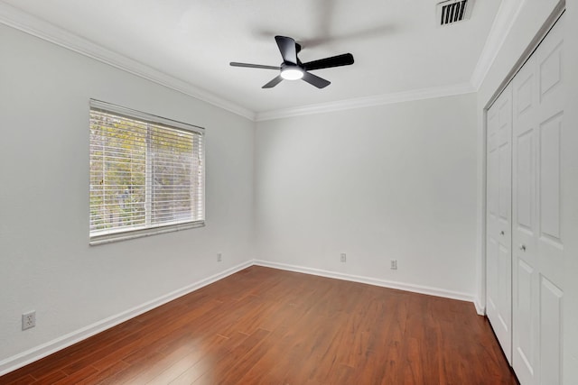 unfurnished bedroom featuring baseboards, visible vents, ornamental molding, dark wood-type flooring, and a closet