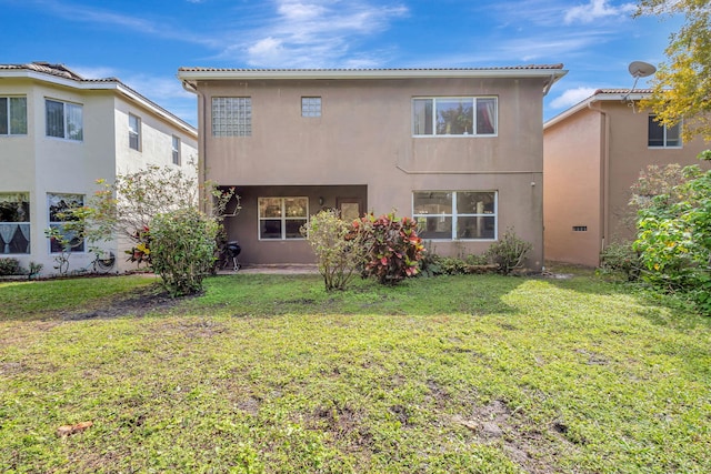 back of house featuring a lawn and stucco siding