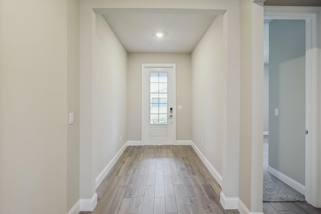 doorway to outside featuring baseboards and wood finished floors