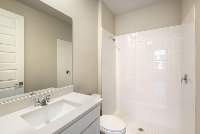 bathroom featuring toilet, vanity, and a tile shower