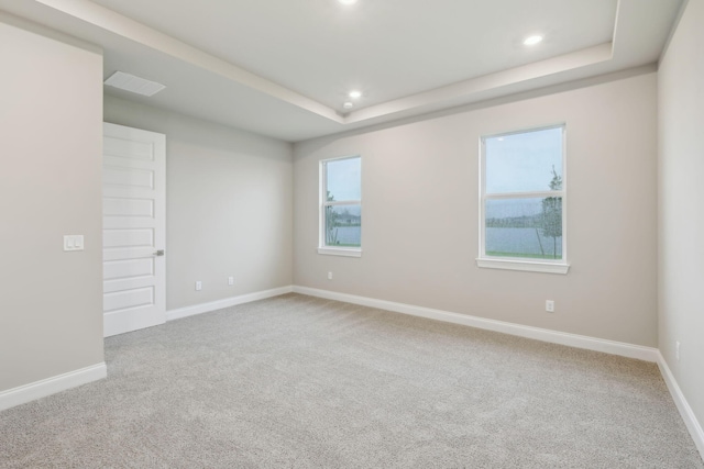 carpeted spare room featuring visible vents, a tray ceiling, baseboards, and recessed lighting