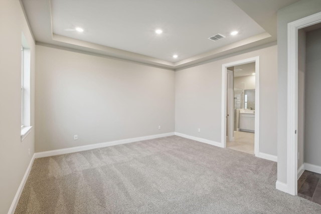unfurnished bedroom with visible vents, recessed lighting, carpet, and a raised ceiling